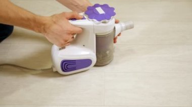 Elektrik süpürgesi konteynırı. Adam çöpü yere döktü.