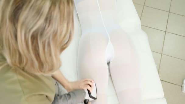Dame in groene jas maakt lipomassage op salon patiënt benen — Stockvideo