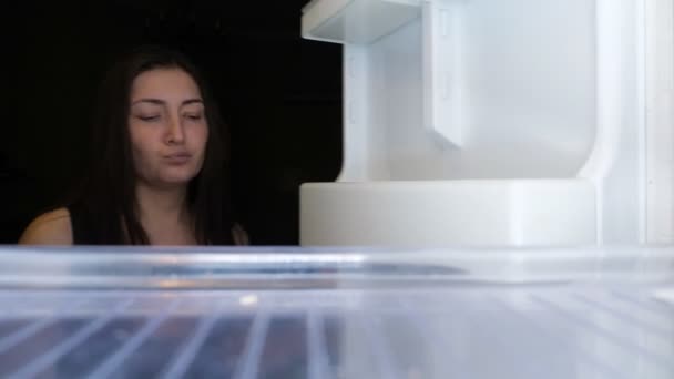 Женщина открывает холодильник и садится на шоколадную диету — стоковое видео