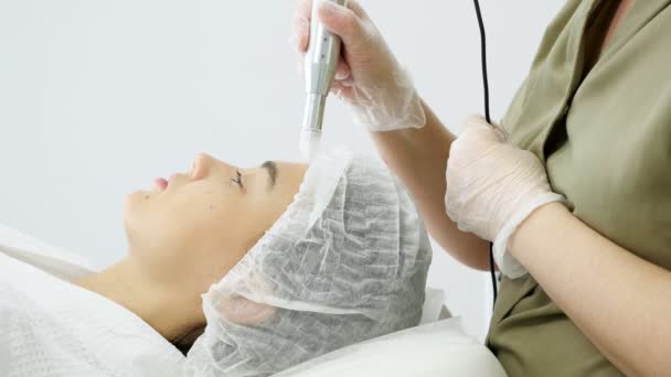 Kosmetikerin bewegt Mikrodermabrasionsgerät auf der Stirn — Stockvideo