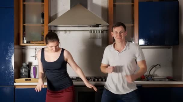 Boldog férfi és nő tánc és ugrik fel szórakozás a konyhában — Stock videók