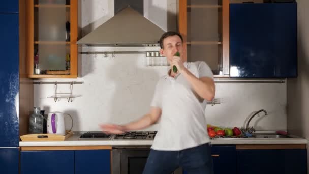 Man sings using cucumber as microphone and grimaces jumping — Stock Video