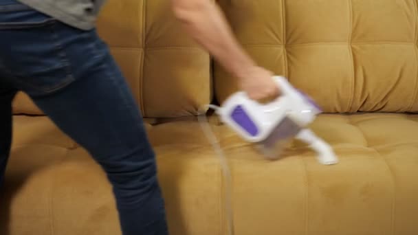 Άνθρωπος σε τζιν για να καθαρίσετε τον καναπέ με ηλεκτρική σκούπα — Αρχείο Βίντεο