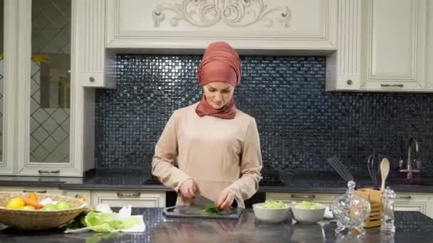 Orientalische Frau kocht Mahlzeit und schneidet frisches Grünzeug lächelnd — Stockvideo