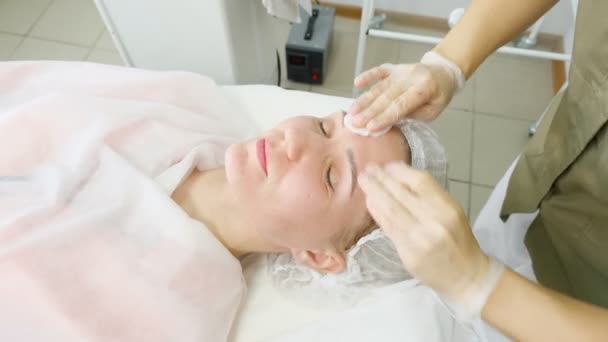 Θεραπευτής σε λευκά αποστειρωμένα γάντια ξεπλένει το πρόσωπο του ασθενούς κοντά — Αρχείο Βίντεο