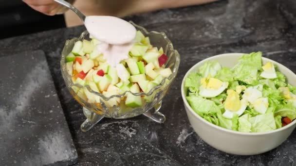 Женщина наливает йогурт на приготовленный фруктовый салат на завтрак — стоковое видео