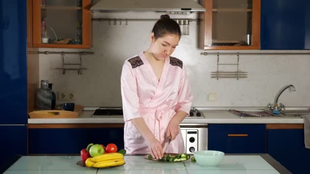 Chica hace ensalada de pie en la mesa y cortar verduras — Vídeos de Stock