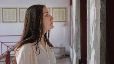 Kadın yarı yüzlü ve müzede bilgi okuyor.