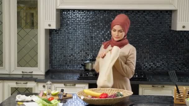 Mujer viene a la cocina bolsa de transporte y saca los productos — Vídeos de Stock