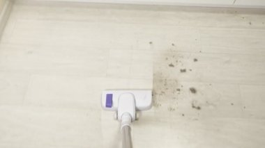 Elektrik süpürgesinin yakın çekimi. Yerdeki toz ve moloz yığınını temizliyorum. Yukarıdan görünüşü