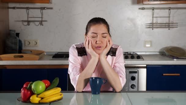 Chica se sienta a la mesa con una taza de café y se duerme — Vídeos de Stock