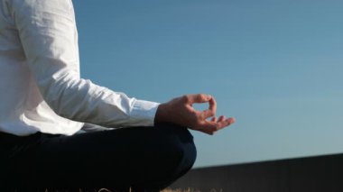man in white shirt and black pants meditates under clear sky