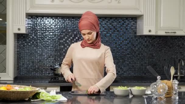 Восточная женщина готовит еду, режет свежую зелень, улыбаясь — стоковое видео