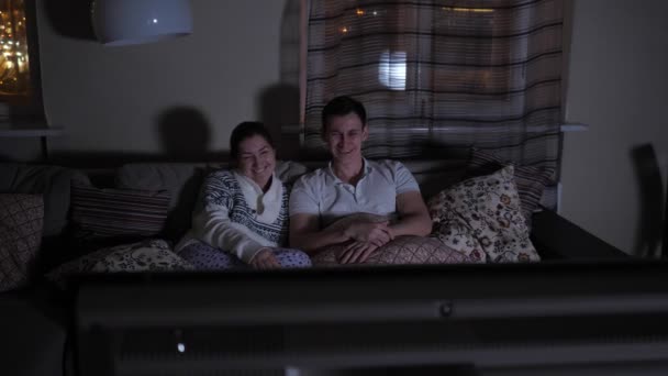 Hombre y mujer viendo una película divertida en la oscuridad — Vídeo de stock