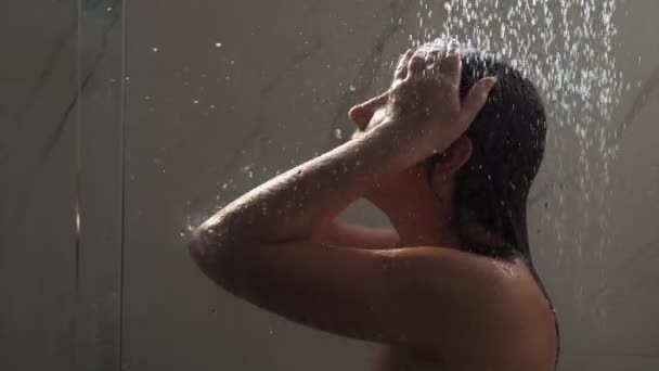 Jeune femme court les mains sur le visage debout sous l'eau de douche — Video