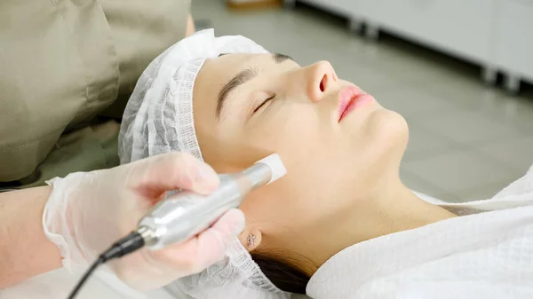 Lady in green coat makes microdermabrasion procedure on face — Stock Photo, Image