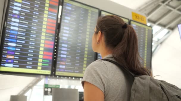 Morena olha para o horário de partidas no terminal do aeroporto — Vídeo de Stock