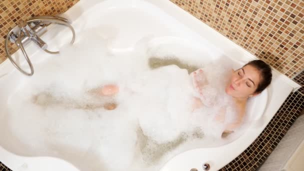在按摩浴缸里玩泡沫的漂亮女人从顶部看问题 — 图库视频影像