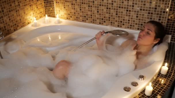 Joven mujer canta en un baño de burbujas a la luz de las velas — Vídeos de Stock