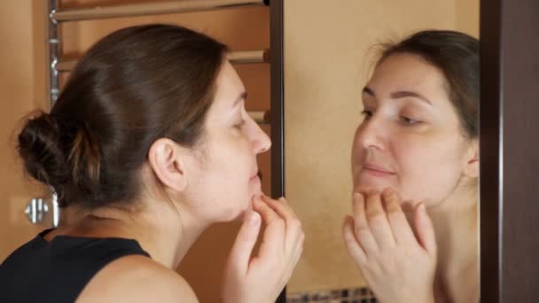 Chica joven en el cuarto de baño se ve granos en frente del espejo . — Vídeos de Stock