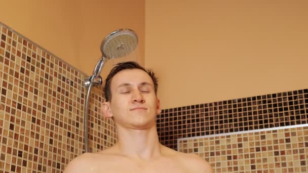 Homem bonito está de pé sob o chuveiro — Vídeo de Stock