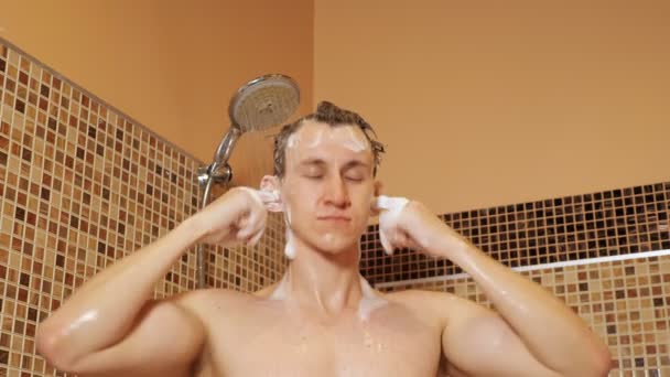 Jeune homme se lave les cheveux sous la douche — Video