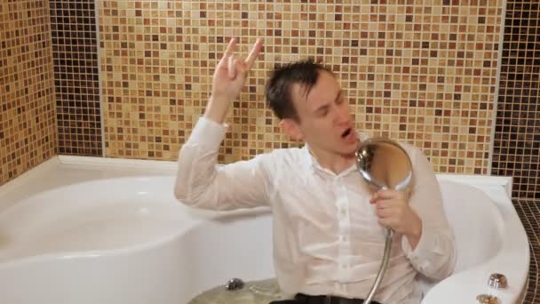 Pijany biznesmen śpiewa w wannie z wodą, leżąc w ubraniu — Wideo stockowe