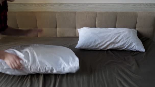 Lady hands beat white pillow and throw on large brown bed — Stock Video