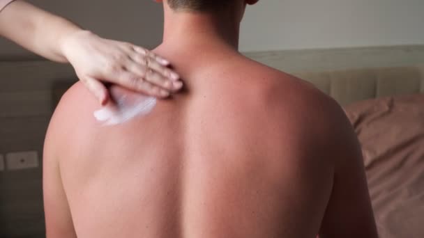 Joven mujer mano cubre muscular hombre espalda con blanco crema — Vídeos de Stock