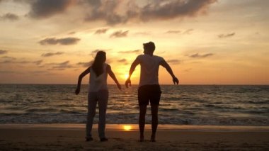 Neşeyle atlayan çiftler dalgalar halinde deniz kıyısında vakit geçirir.