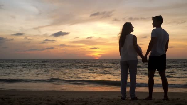 Silhouet van koppel dat tijd doorbrengt aan kust hand in hand — Stockvideo