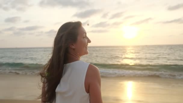 Веселая дама в белом платье бежит вдоль берега моря вечером — стоковое видео