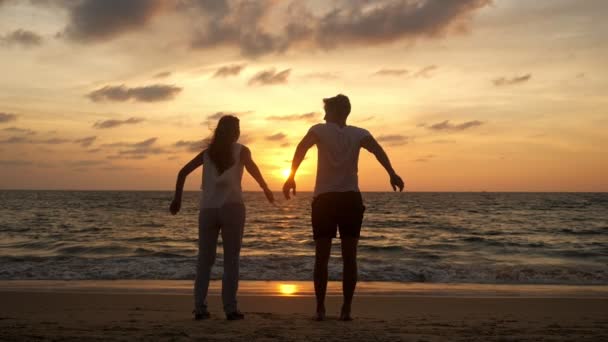 Пара прыгает с радостью, проводя время на берегу моря волнами — стоковое видео