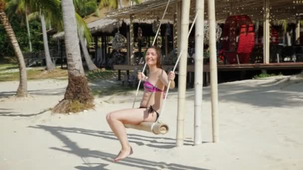 Jonge vrouw in bikini op een swing — Stockvideo