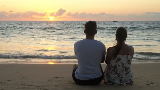 Encantadora pareja joven se sienta en la playa del océano — Vídeo de stock