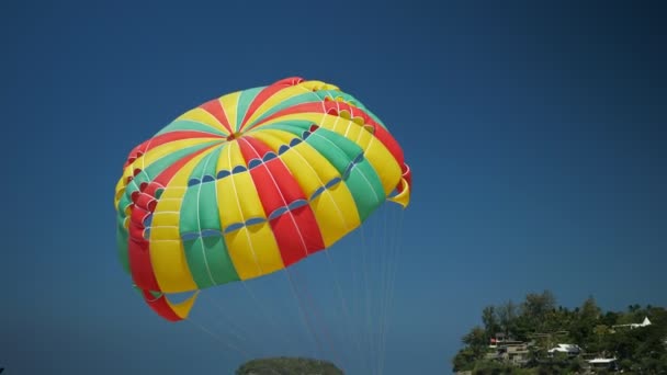 Prachtige rode groene en gele parachute onder de blauwe hemel — Stockvideo