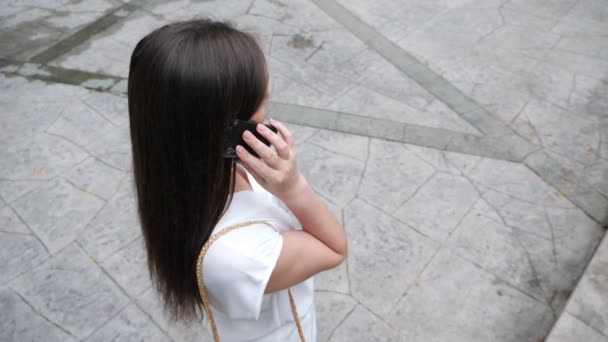 Brunette parle sur smartphone noir et laisse tomber le téléphone sur la route — Video