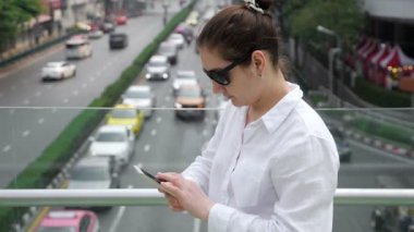 Beyaz elbiseli esmer. Köprüdeki akıllı telefondan arıyor.