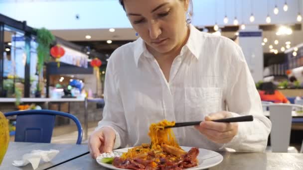 Молодая женщина ест палочки для еды лапшу — стоковое видео