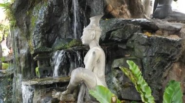 Beyaz taş, temiz şelale yakınlarında Buda heykeli üzerinde meditasyon yapıyor.