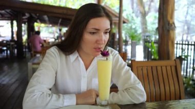 Genç bayan bir kafede meyve kokteyli içiyor.