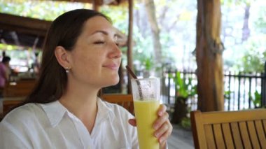 Beyaz gömlekli kadın smoothie içiyor.