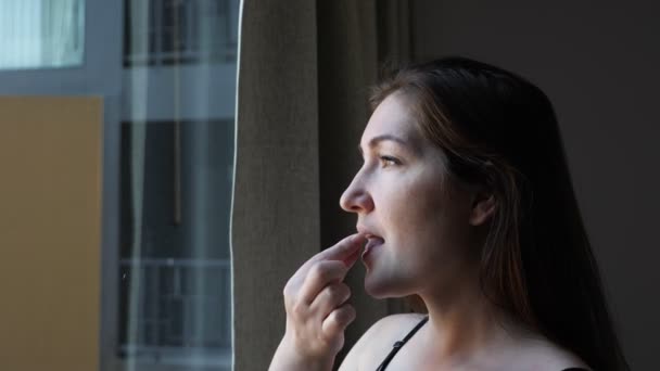 Позитивная женщина принимает таблетки и пьет воду в номере отеля — стоковое видео