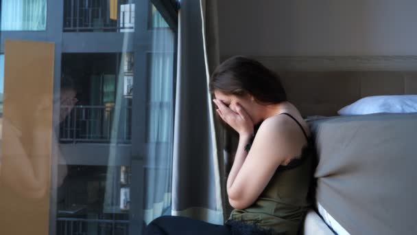 Mulher sonolenta senta-se perto da cama e janela em hotel confortável — Vídeo de Stock