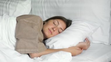 Mutlu kadın, otelde battaniye ve yastıklarla uyuyor.