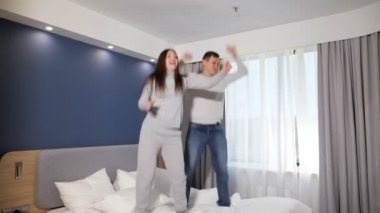 Erkek ve kadın otelin penceresine karşı yatağa atlıyorlar.