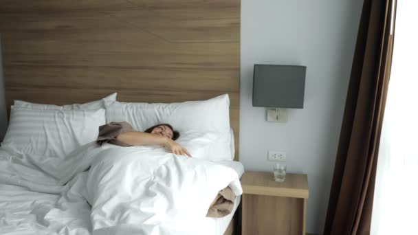 Дівчина в халаті прокидається і п'є чисту воду в готельному номері — стокове відео
