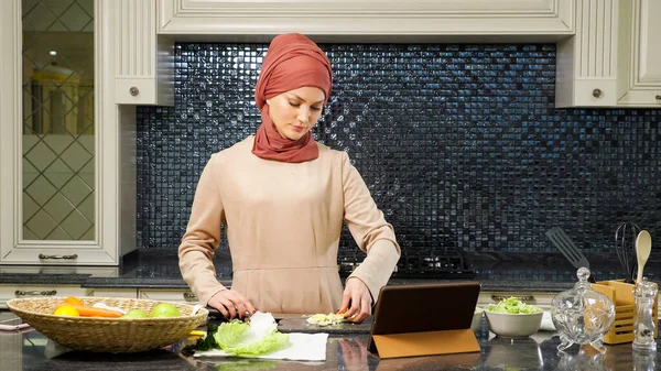 Mulher islâmica cortar legumes assistindo receita prato halal — Fotografia de Stock