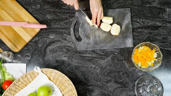 Dona de casa corta maçã cozinhando salada de frutas na mesa da cozinha — Fotografia de Stock