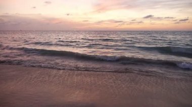 Boş kumsalda okyanus dalgalarıyla harika bir gün batımı.